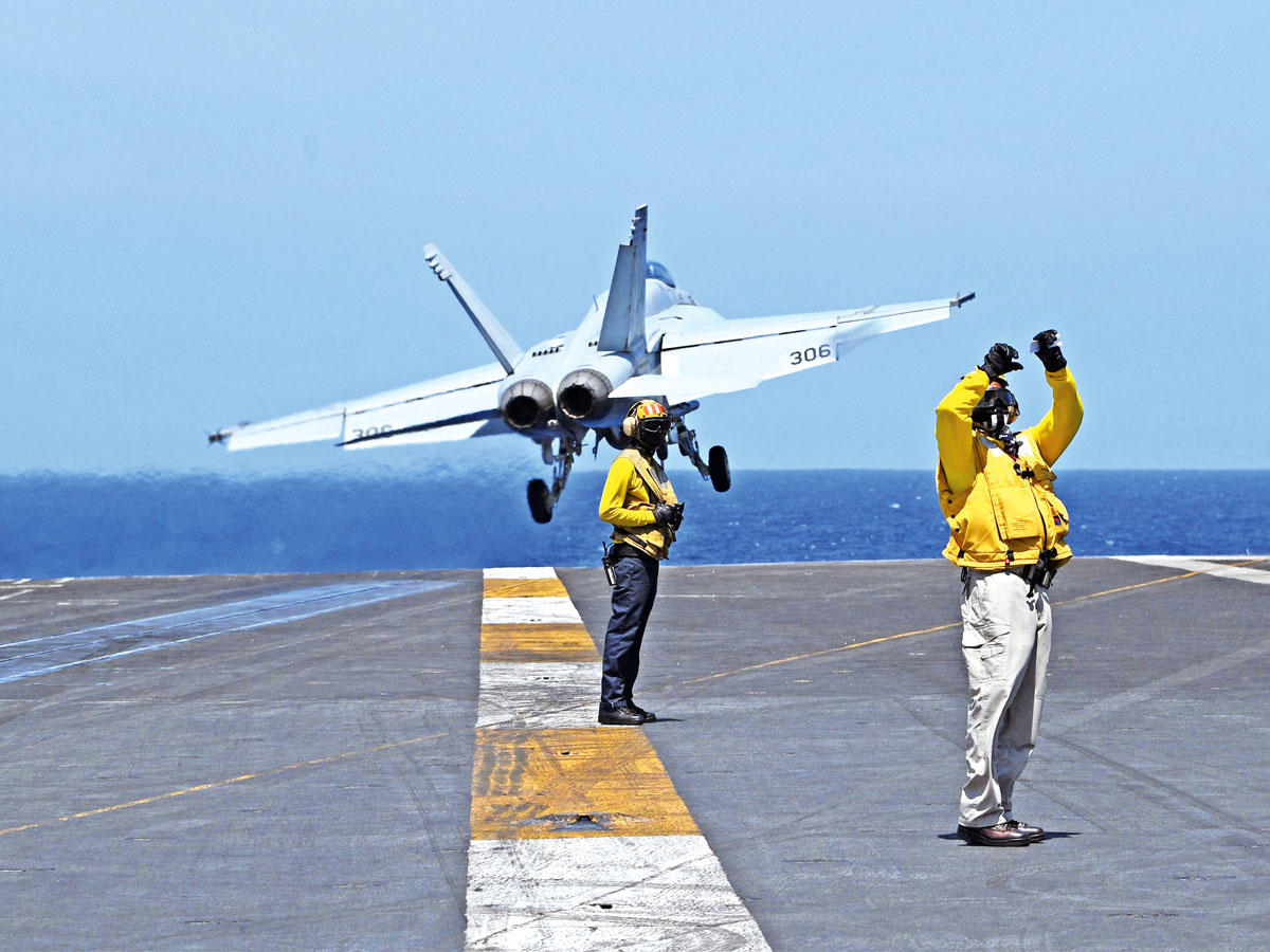 بحار أميركي يأذن لطلعة مقاتلة FA-18 على حاملة الطائرات «ثيودور روزفلت» في بحر الصين أمس (أ ف ب)