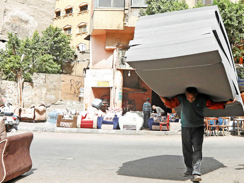 عامل يحمل فرشات من الإسفنج في أحد أسواق القاهرة أمسt(رويترز)