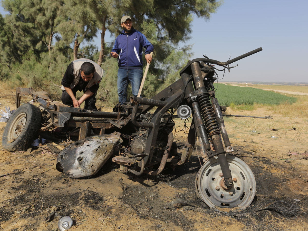 رجلان يتفحصان دراجة بخارية مدمرة بعد انفجار شرق مدينة رفح جنوب قطاع غزة