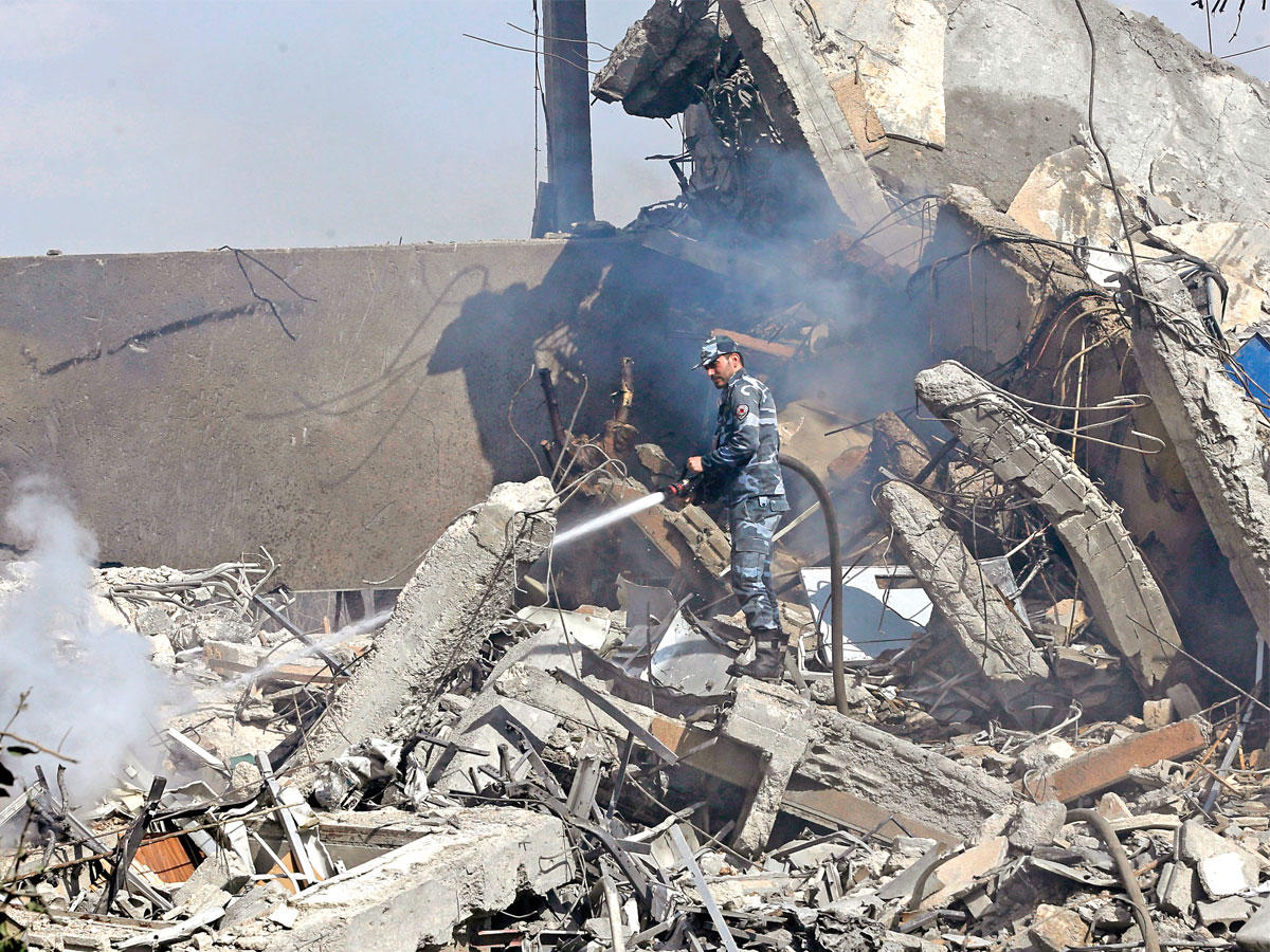 جندي سوري يحاول إخماد النيران بمركز البحوث في حي برزة شمال دمشق أمس  (أ ف ب)