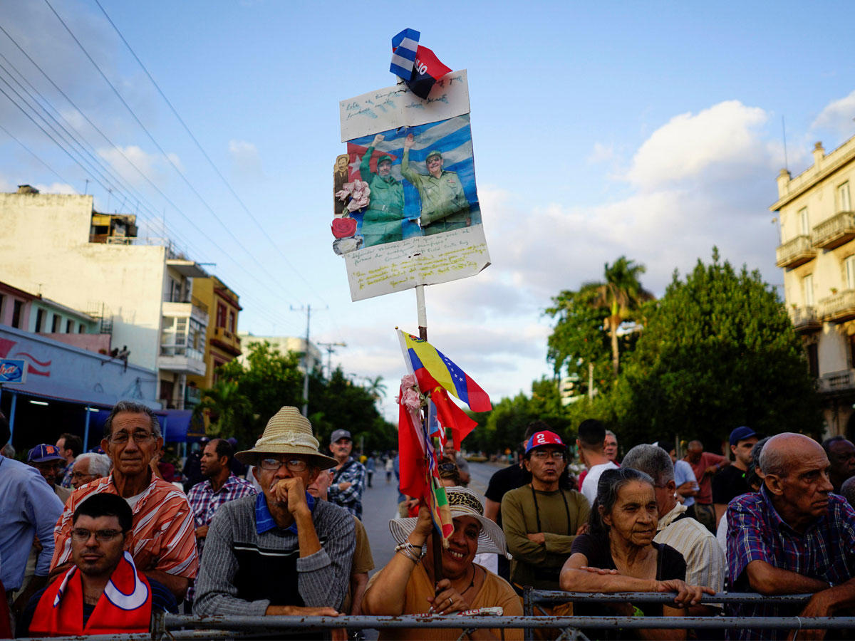 امرأة تحمل صورة الرئيس الكوبي السابق الراحل فيدل كاسترو والرئيس الكوبي راؤول كاسترو