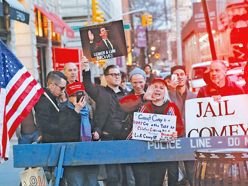 مناصرون لترامب يحملون شعارات مناهضة لجيمس كومي أمام دار «بارنز ونوبل» للنشر في نيويورك أمس الاول بالتزامن مع بدء نشر كتابه (رويترز)