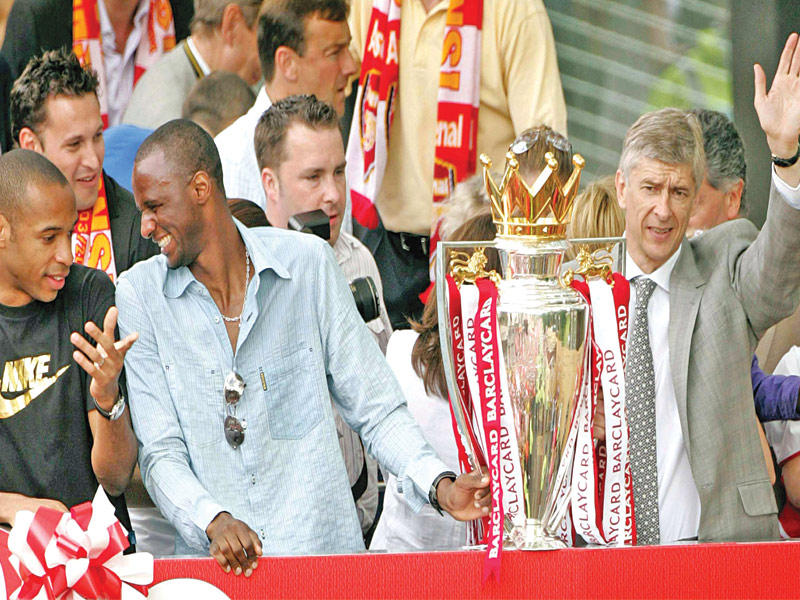 أرسين فينغر إلى جانب باتريك فييرا وتيري هنري خلال الاحتفال بلقب الدوري الإنكليزي عام 2004