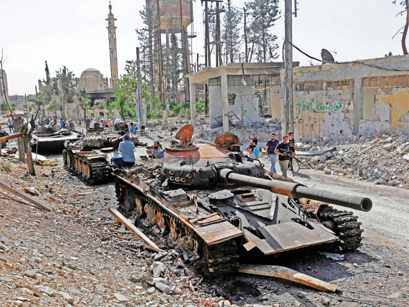 دبابات مدمرة وناقلات جند على جانب الطريق في دوما أمس (أ ف ب)