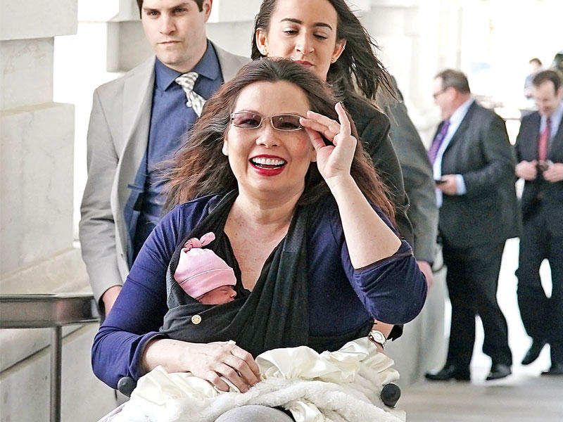  السيناتور تامي داكوورث وطفلتها على كرسيها المتحرك في طريقها إلى مبنى الكابيتول أول من أمس (أ ف ب) 