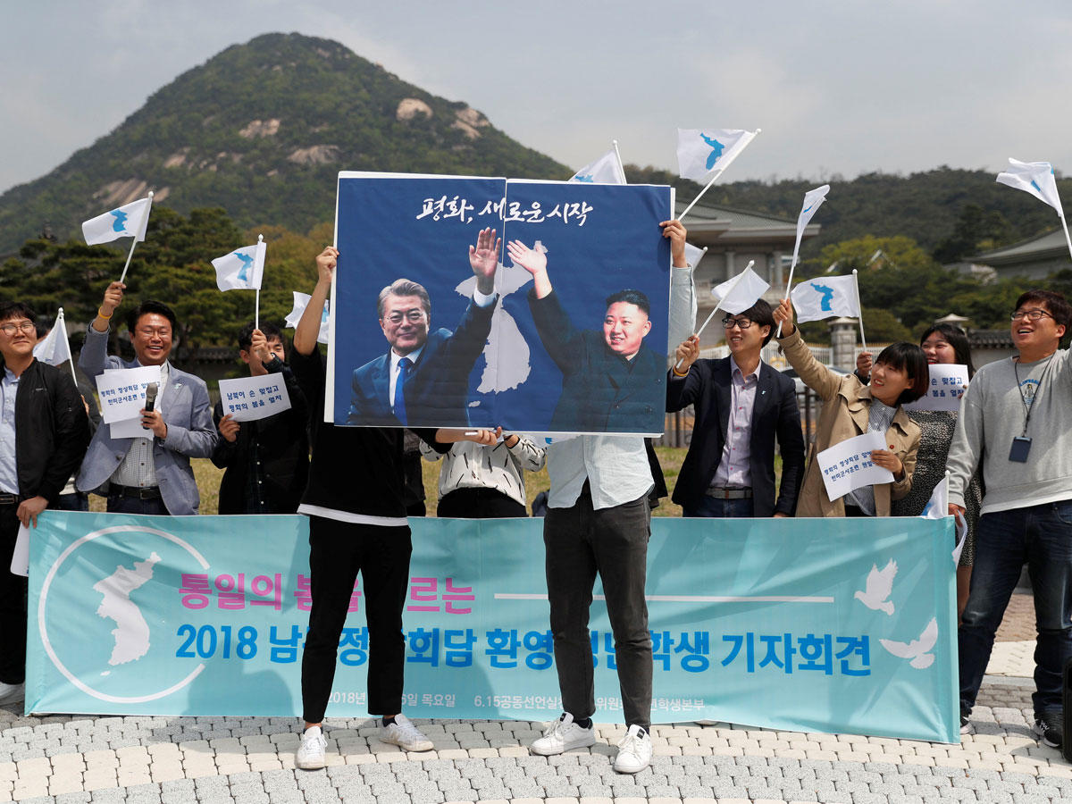 طلاب في سيول يرفعون صورة كيم ومون فرحاً بقمة اليوم    (رويترز)