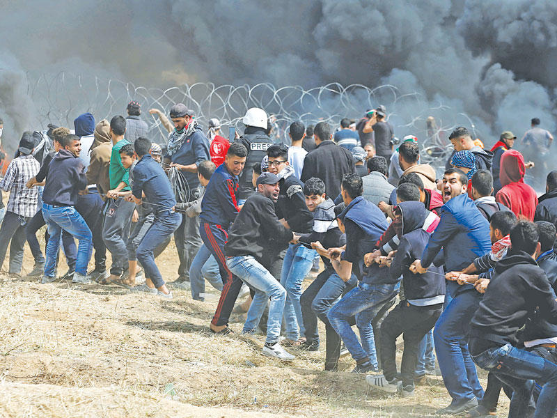  فلسطينيون يزيلون سياجاً حديدياً وضعته إسرائيل على خط غزة أمس (أ ف ب) 