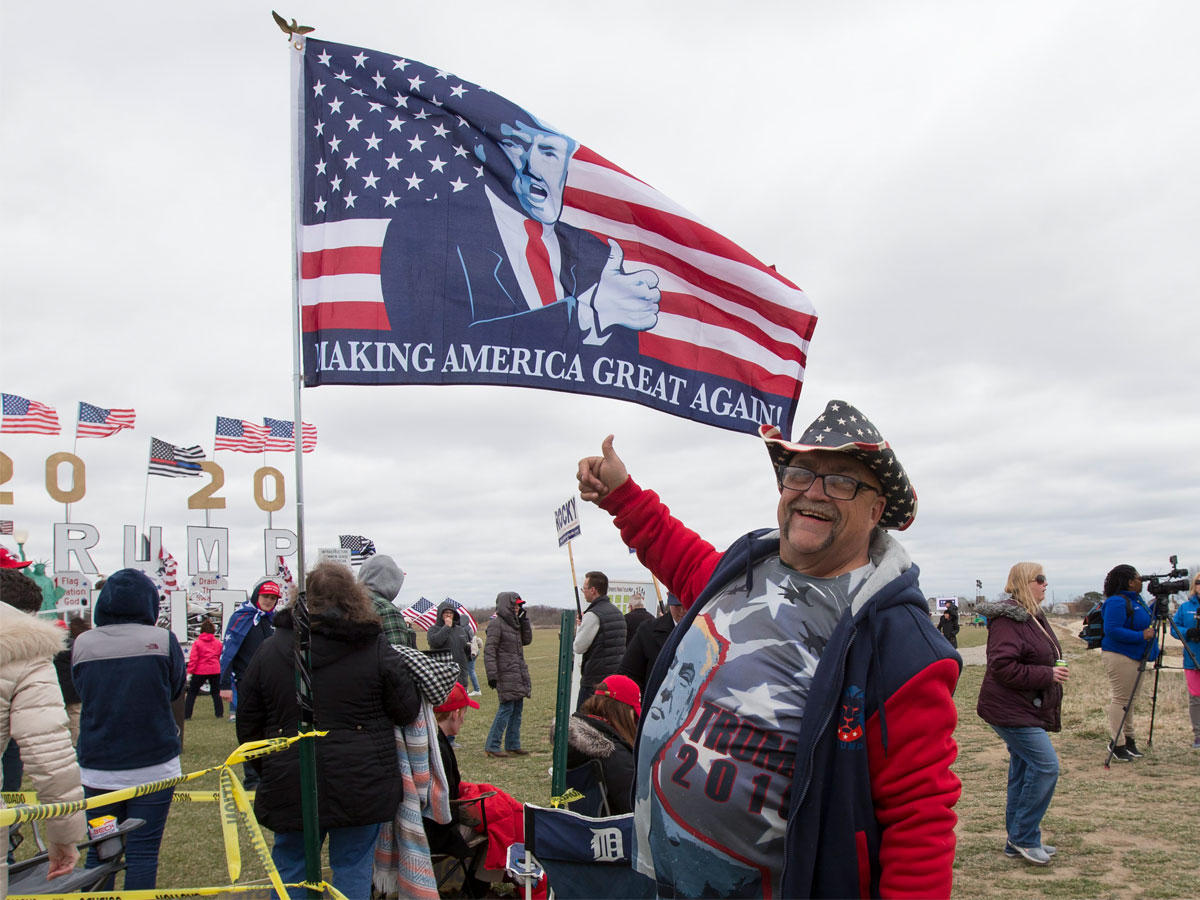 أحد مؤيدي الرئيس الأميركي يقف تحت علم يحمل صورة ترامب في ميتشيغان    (اي بي آي)