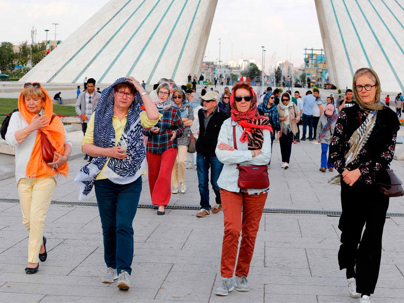سياح بمحيط برج آزادي في طهران أمس وسط أنباء عن صعوبات في استبدال العملة المحلية بالدولار مع اشتداد الأزمة الاقتصادية جراء زيادة المخاوف من احتمال عودة العقوبات الأميركية الاقتصادية على إيران (أ ف ب)