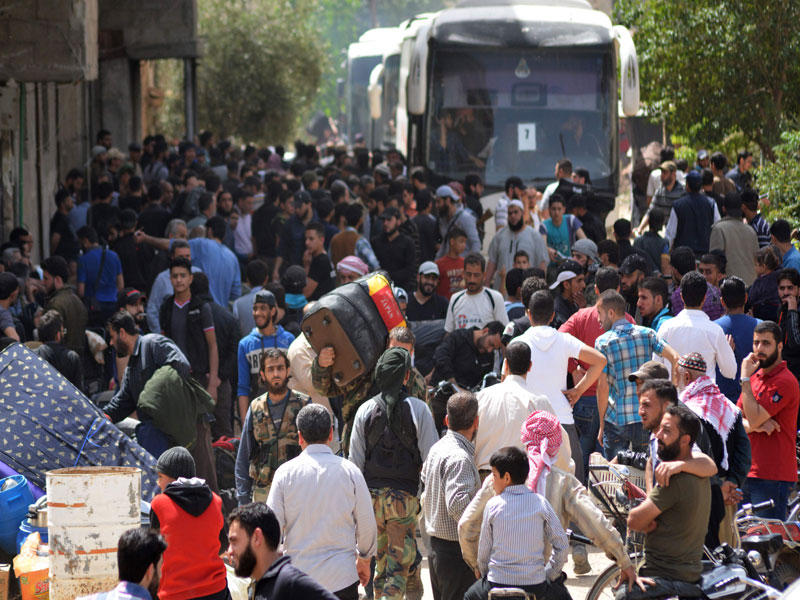 مقاتلو المعارضة وعائلاتهم يستعدون للخروج من يلدا جنوب دمشق أمس باتجاه الشمال  (أ ف ب)