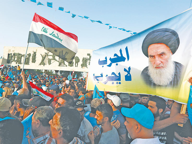 أنصار الصدر يحملون صورة للسيستاني في ساحة التحرير ببغداد أمس الأول (رويترز)