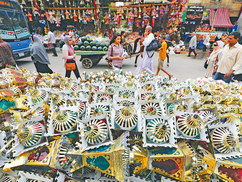 مصريون يمرون أمام بائع فوانيس رمضان في القاهرة (رويترز)
