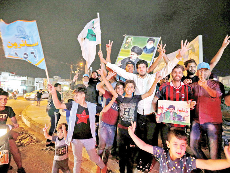 عراقيون يحتفلون بفوز قائمة سائرون ويرفعون صور مقتدى الصدر وسط بغداد مساء أمس الأول  (رويترز)