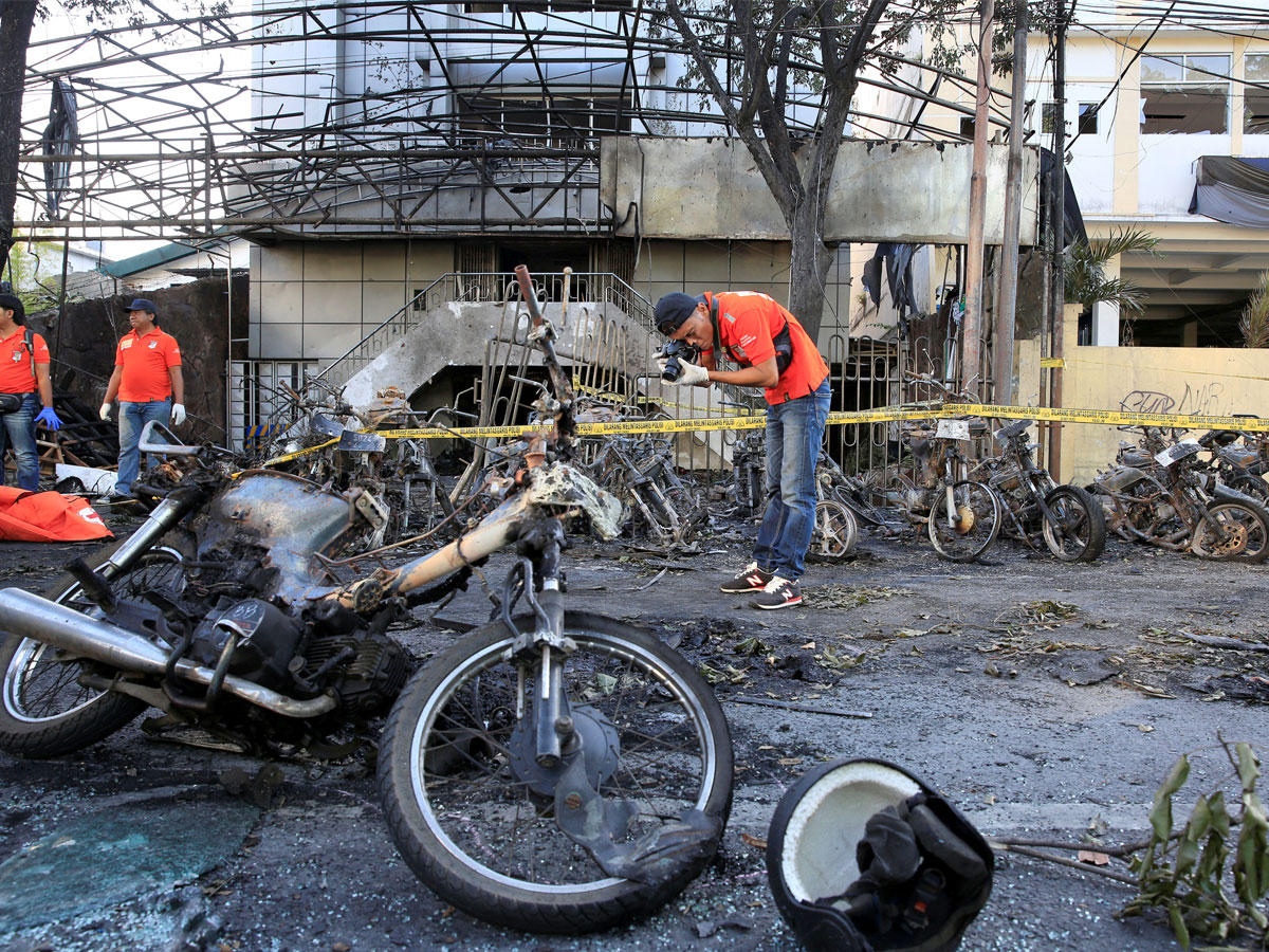 ضابط شرطة شرعي يلتقط صوراً للحطام بالقرب من دراجات نارية محترقة بعد انفجار في كنيسة