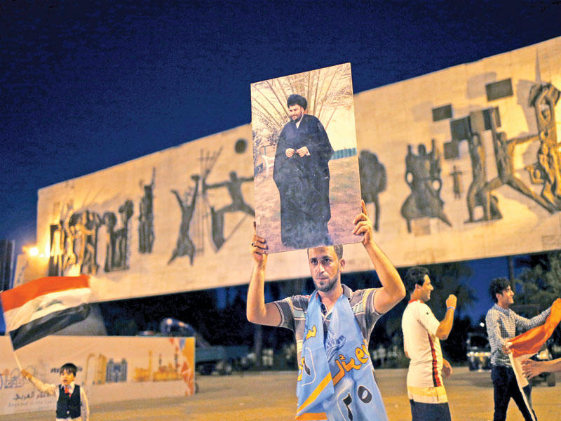 عراقي يرفع صورة الصدر في ساحة التحرير ببغداد مساء أمس الأول (رويترز)