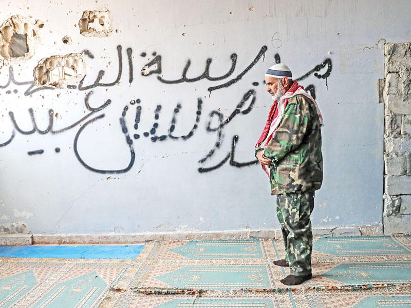 سوري مهجر من الغوطة يصلي في مدرسة بالأتارب شمال سورية (أي بي ايه)