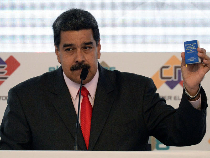 الرئيس الفنزويلي نيكولاس مادورو ، يحمل الدستور أثناء حديثه ، في مقر المجلس الوطني للانتخابات في كاراكاس