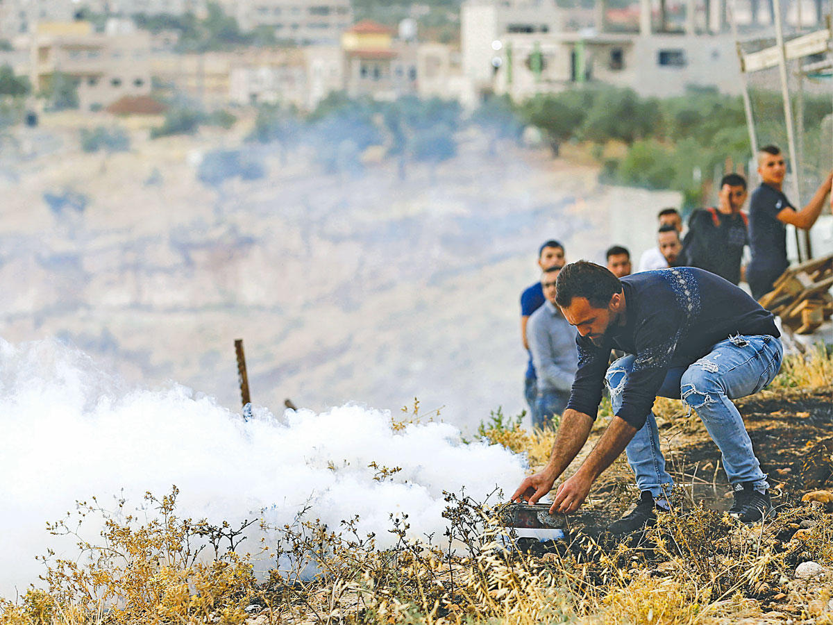 فلسطيني يتصدى لقنبلة غاز بمواجهات في بيت لحم أمسt(رويترز)