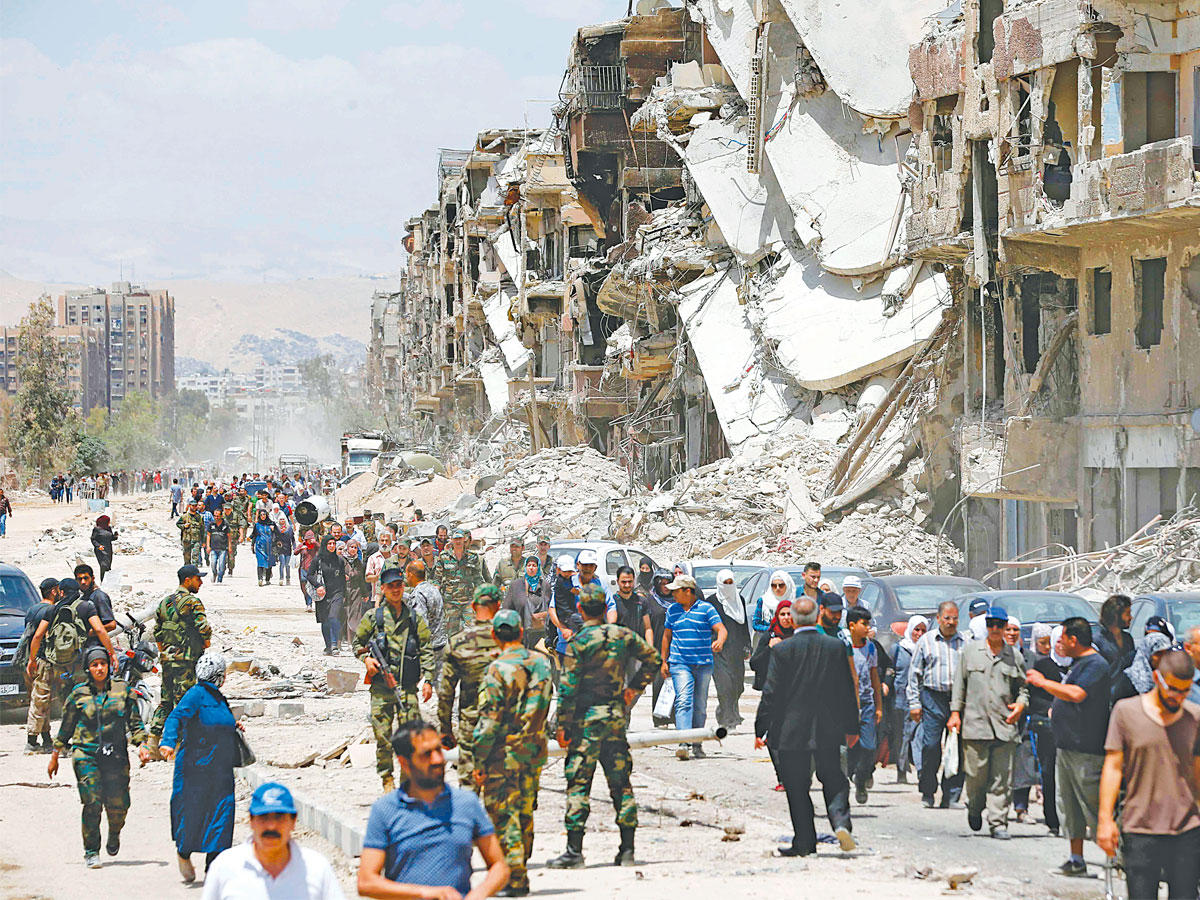 مدنيون وعسكريون في شارع التلاثين المدمر بمخيم اليرموك أمس الأول (أ ف ب)n