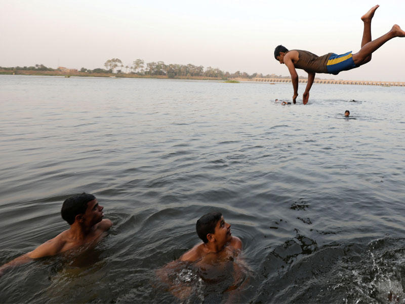 شباب مصريون يسبحون بسبب ارتفاع حرارة الجو على غير المعتاد في شهر رمضان على مشارف القاهرة قبل يومين (رويترز)