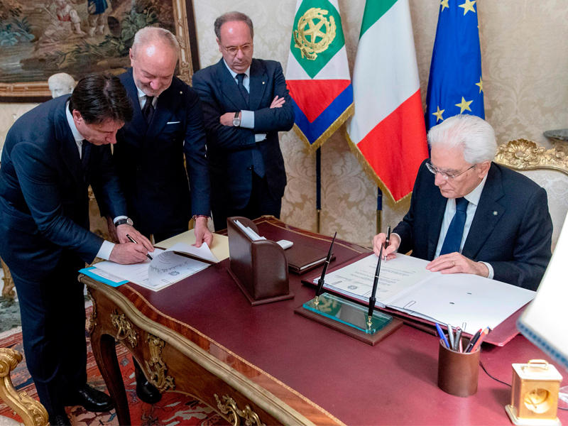 كونتي (إلى اليسار) يوقّع أمام الرئيس ماتاريلا لائحة الوزراء الجدد  (أ ف ب)