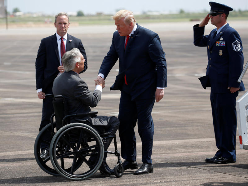 ترامب مصافحاً حاكم تكساس لدى وصوله أمس الأول إلى هيوستن (رويترز)