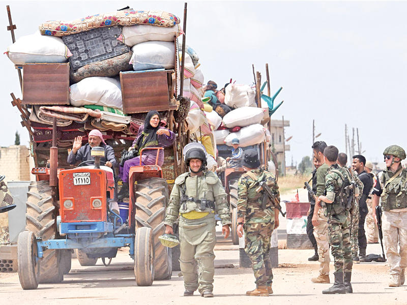 جنود روس يتابعون تفقد قوات النظام لقافلة تقل نازحين عائدين إلى مناطق سيطرتها في ريف إدلب أمس الأول (أ ف ب)