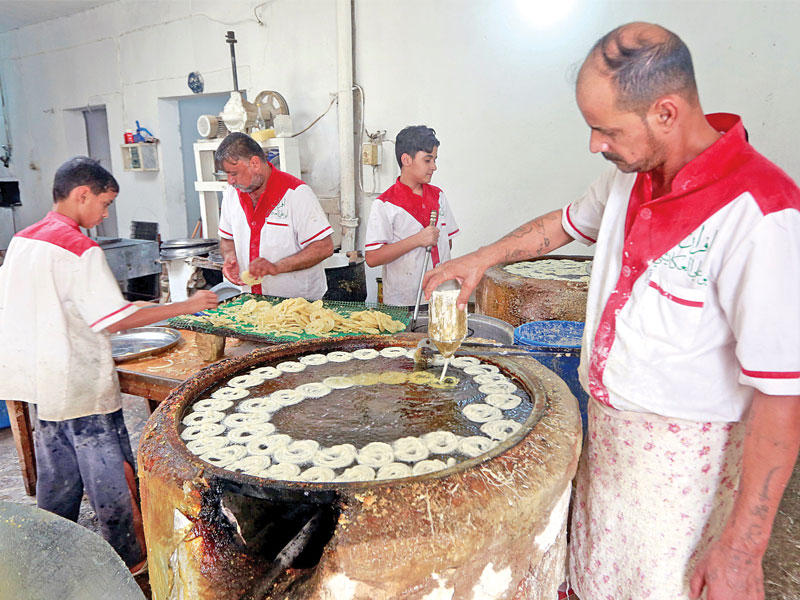 عراقيون يعملون في محل للحلويات في النجف  (رويترز)