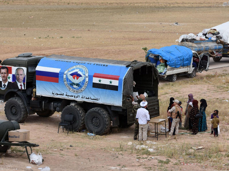 أفراد من الشرطة العسكرية الروسية يوزعون مساعدات غذائية على السوريين