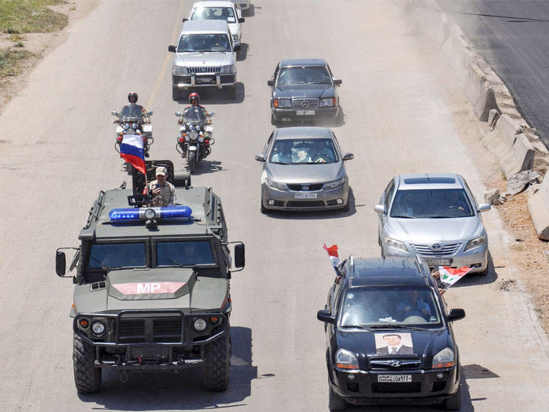 سوريون يواكبون انتشار قوة من الشرطة العسكرية الروسية في حمص أمس (أ ف ب)