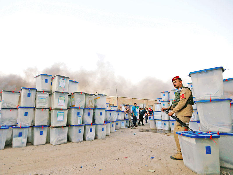 عدد من صناديق الاقتراع الناجية من الحريق تحت حراسة القوات العراقية في بغداد أمس الأول (رويترز)