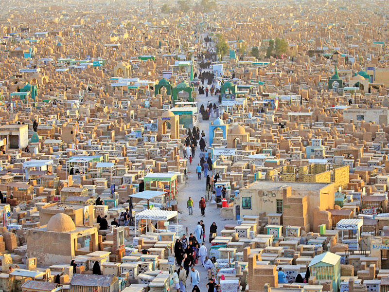 عراقيون يزورون مدافن «وادي السلام» في النجف في أول أيام عيد الفطر لدى مقلدي السيد علي السيستاني (رويترز) 