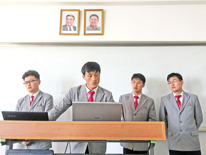 طلاب في جامعة بيونغ يانغ وخلفهما صورة لكيم جونغ اون وجده الراحل كيم سونغ ايل (رويترز)