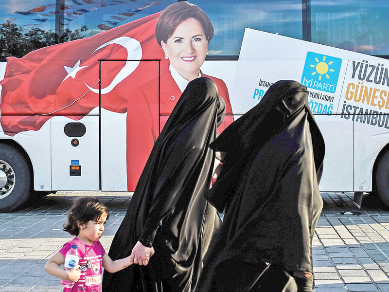سيدتان تمرّان قرب حافلة عليها صورة للمرشحة الرئاسية ميرال اكشينار في إسطنبول أمس tt(أ ف ب)