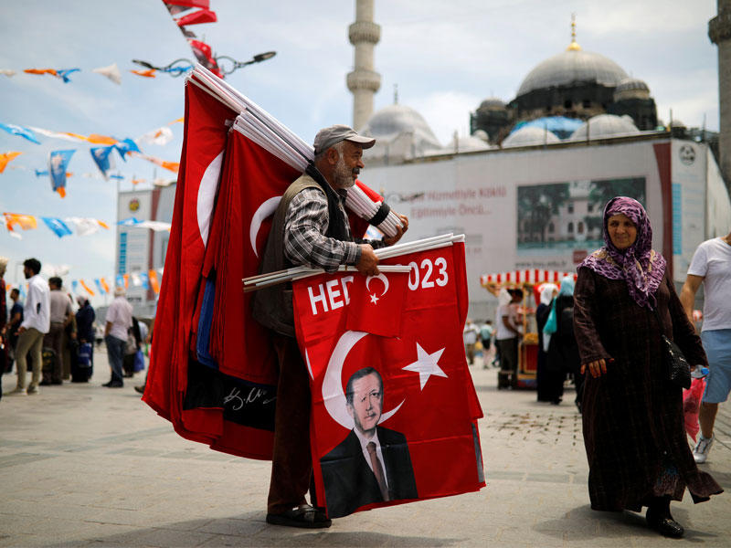 تركي يبيع أعلاماً عليها صورة إردوغان في إسطنبول أمس (رويترز)
