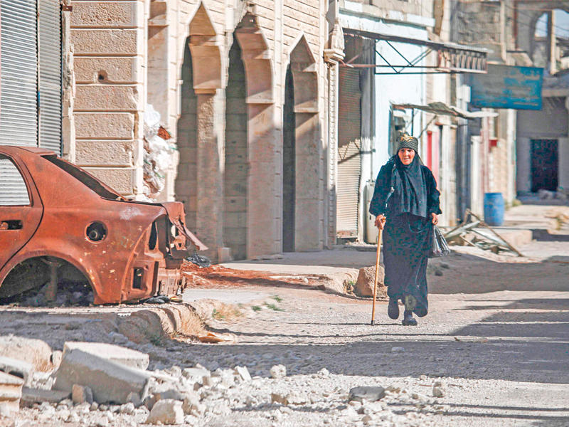 امرأة سورية تسير بين الدمار في مدينة الحراك بمحافظة درعا أمس الأول (أ ف ب)n