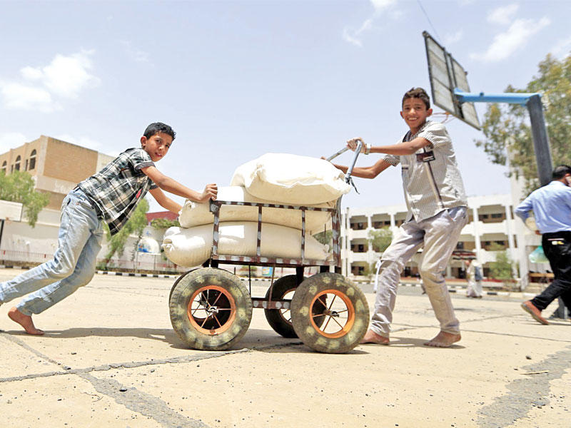 صبيان يدفعان مساعدات غذائية لنازحين من صعدة أمسt(أ ف ب)