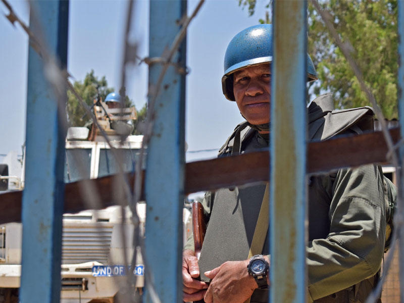 قوات حفظ السلام التابعة للأمم المتحدة تتطلع إلى خلف السياج الشائك عند نقطة تفتيش بالقرب من قرية الرافد السورية في مرتفعات الجولان