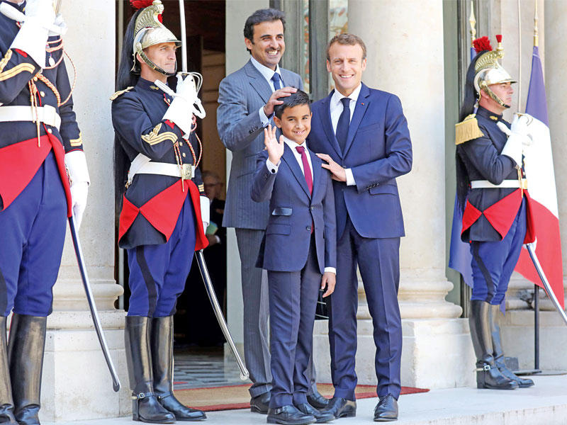 الرئيس الفرنسي إيمانويل ماكرون مستقبلاً أمس أمير قطر الشيخ تميم ونجله حمد على أدراج الأليزيه (أ ف ب)