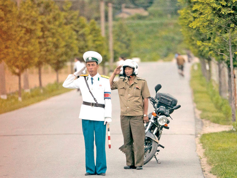 عنصرا أمن كوريان شماليان يؤديان التحية لدى مرور موكب بومبيو في بيونغ يانغ أمس (أ ف ب)