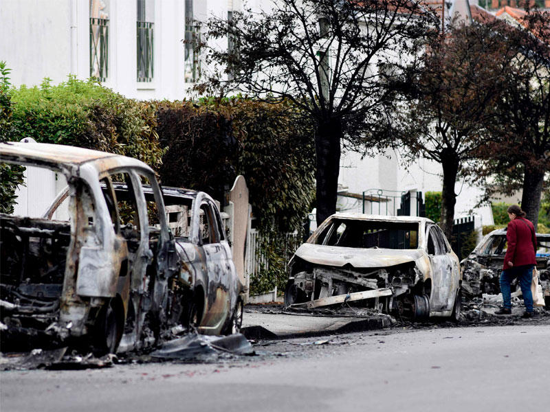 ينظر أحد السكان إلى حطام السيارات المحترقة في حي بلفيو في نانت