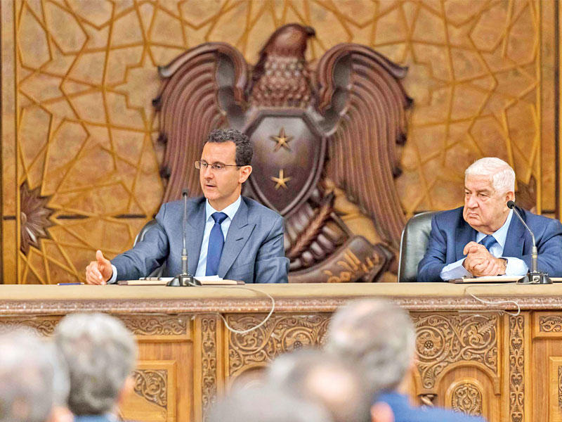 الأسد ووزير خارجيته وليد المعلم خلال لقاء مع  الدبلوماسيين في دمشق أمس t(صفحة الرئاسة السورية)