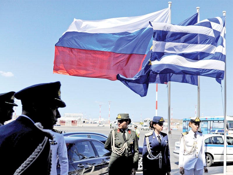 عناصر من الشرطة اليونانية تحت العلمين اليوناني والروسي في أثينا (رويترز)