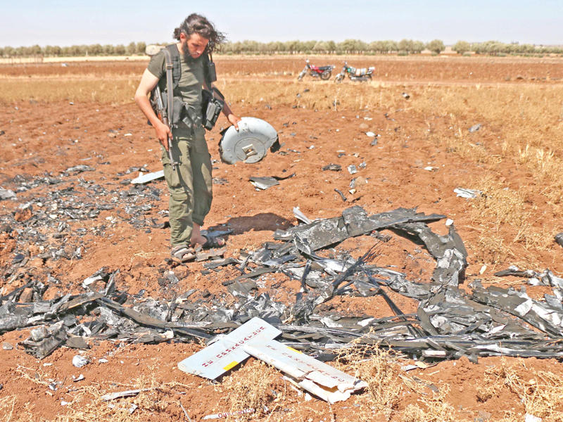 مقاتل سوري يتفقد بقايا طائرة مسيرة أسقطتها إسرائيل قبل يومين قرب الجولان المحتل (أ ف ب)