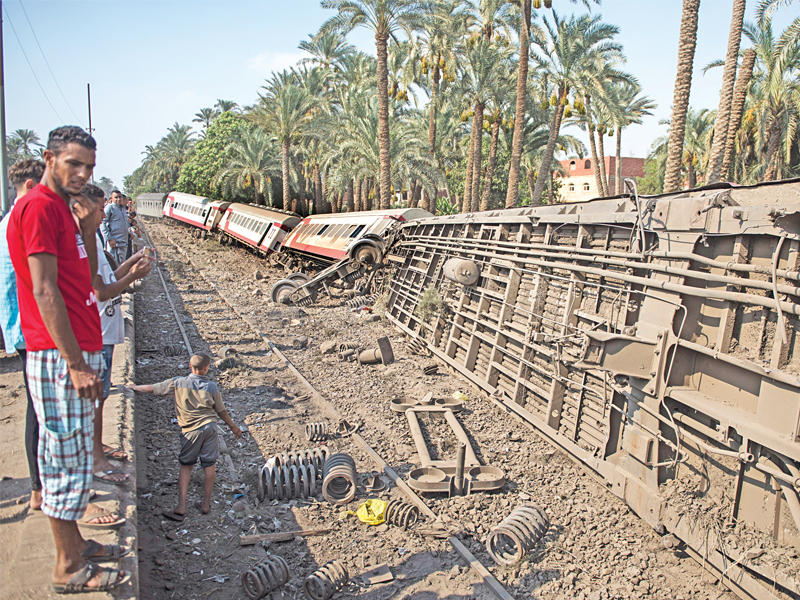 مصريون يتفقدون قطاراً خرج عن مساره، ممأ اسفر عن إصابة 55 في البدرشين بالجيزة أمس (إي بي أيه)