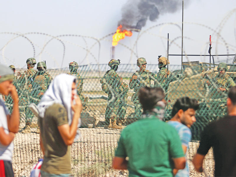 عراقيون ورجال أمن قرب حقل القرنة النفطي (أ ف ب)n