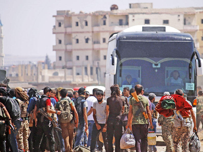 مقاتلون وعائلاتهم يستعدون لمغادرة درعا تحت حماية روسية أمس (أ ف ب)