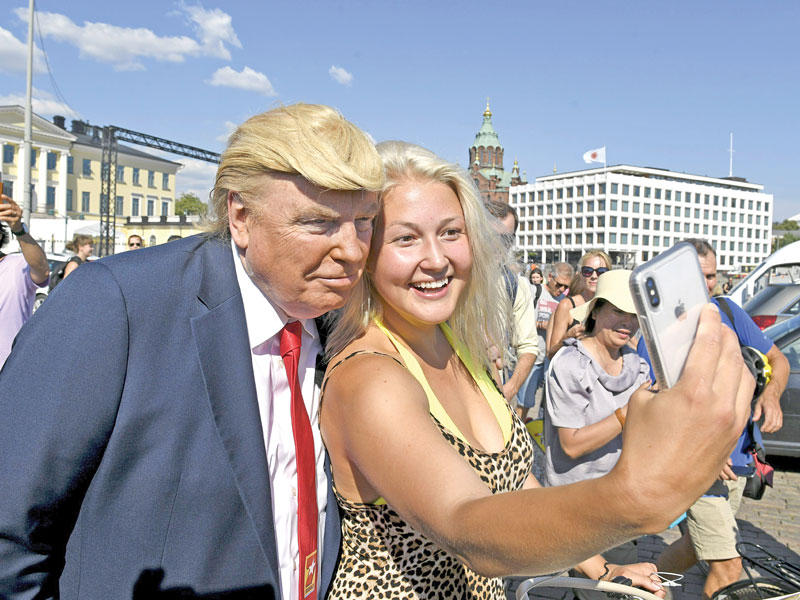 شبيه لترامب يتصور مع امرأة فنلندية  في هلسنكي أمس t(أ ف ب)