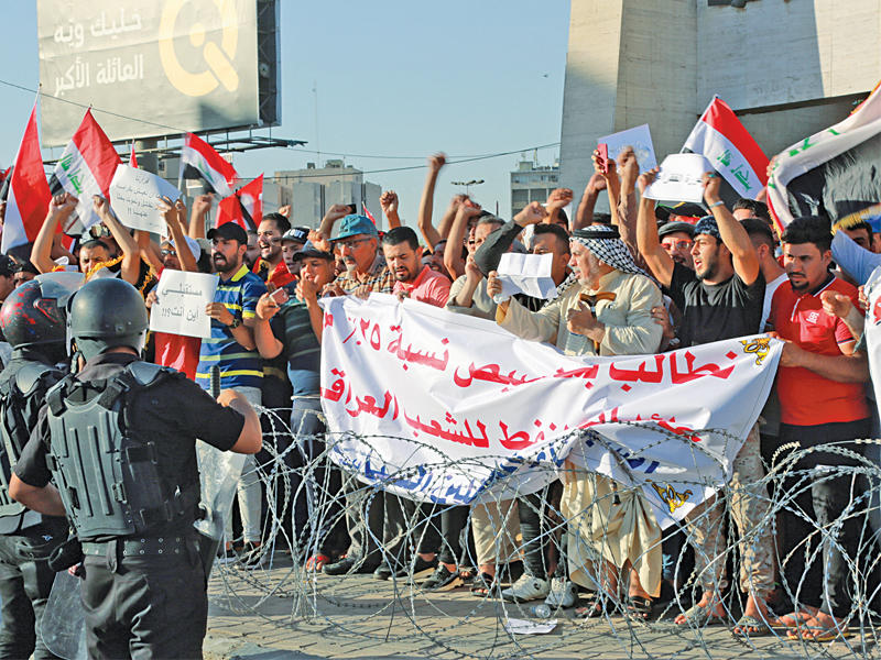 رجال أمن عراقيون بمواجهة المتظاهرين في ساحة التحرير ببغداد أمس الأول (أي بي أيه)