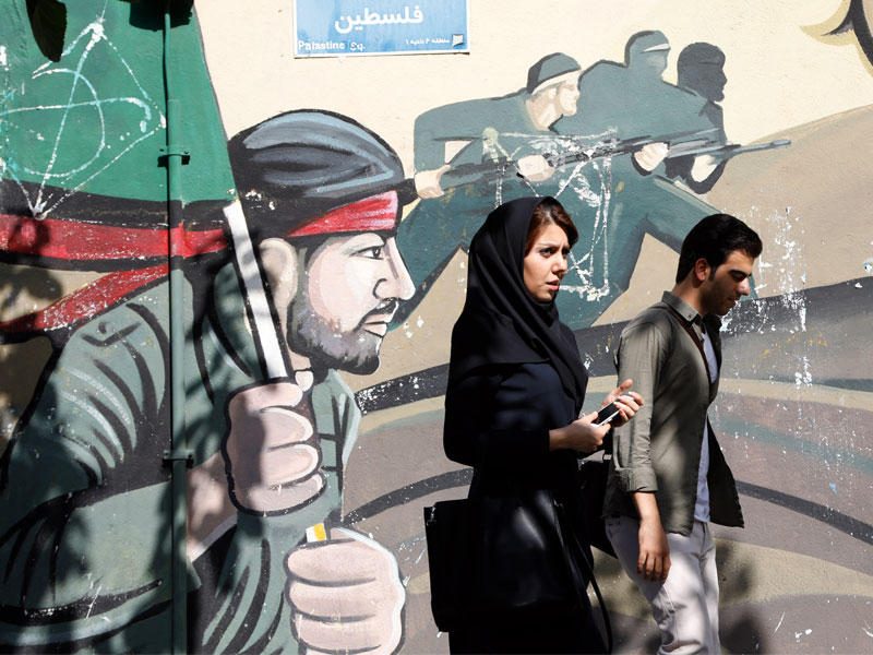 إيرانيان قرب لوحة غرافيتية في طهران أمس (إي بي أيه)